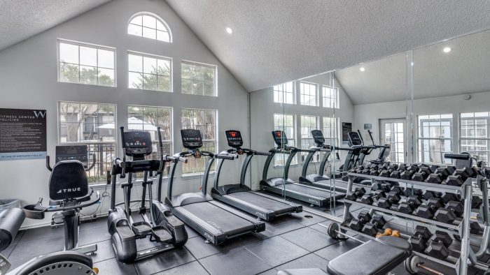 a gym room with tread machines and windows at The Westley