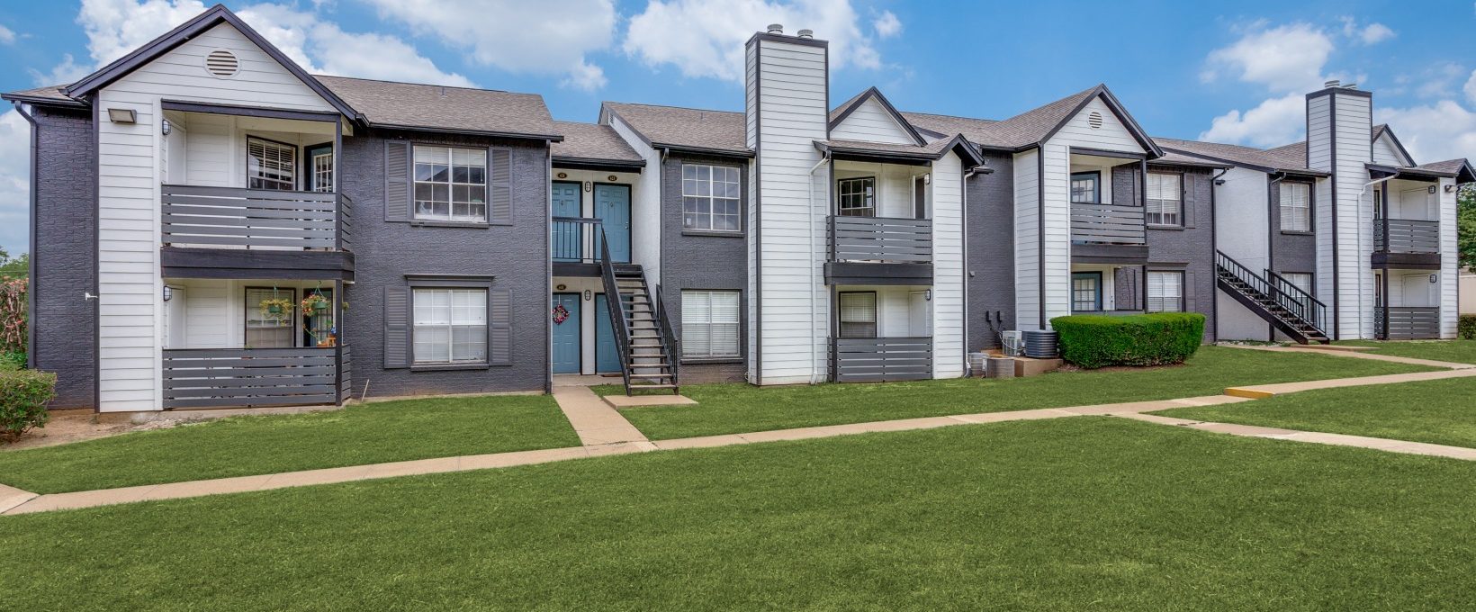 the exterior of an apartment complex with grass and trees at The Westley