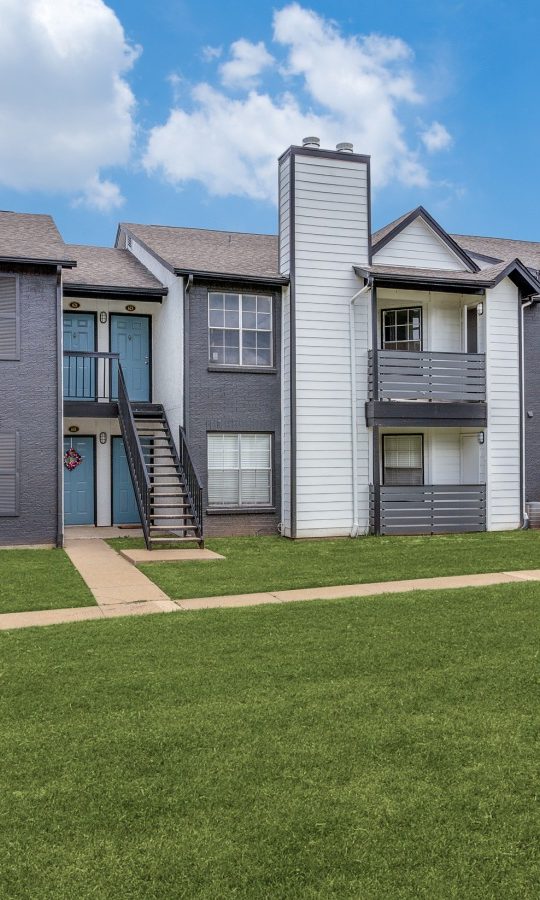 the exterior of an apartment complex with grass and trees at The Westley
