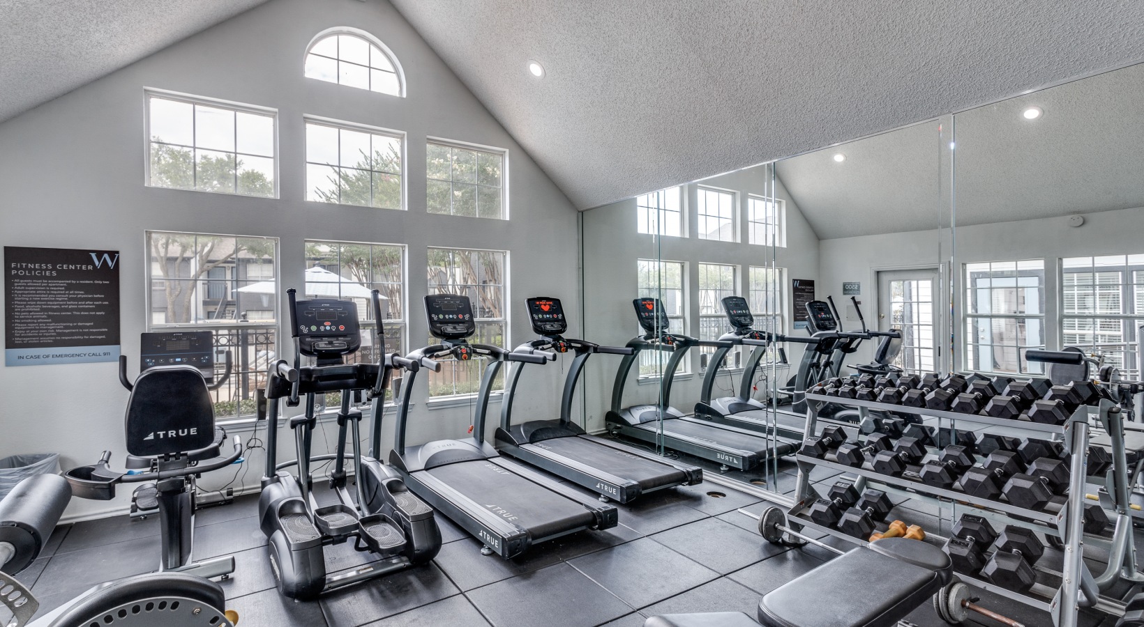 a gym room with tread machines and windows at The Westley