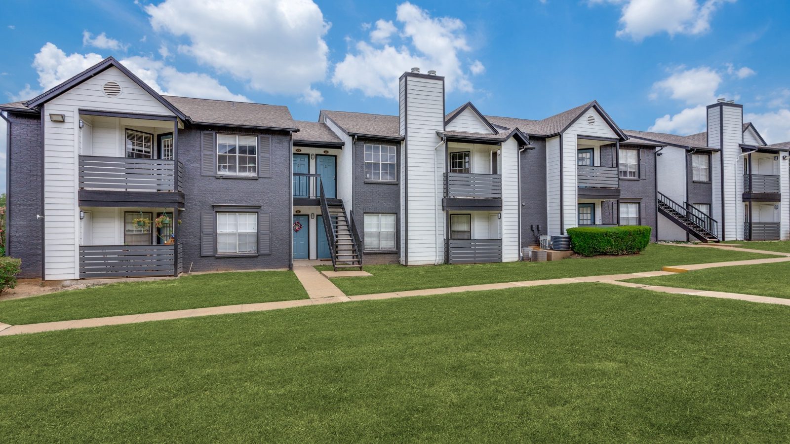 the exterior of an apartment complex with grass and trees at The Westley