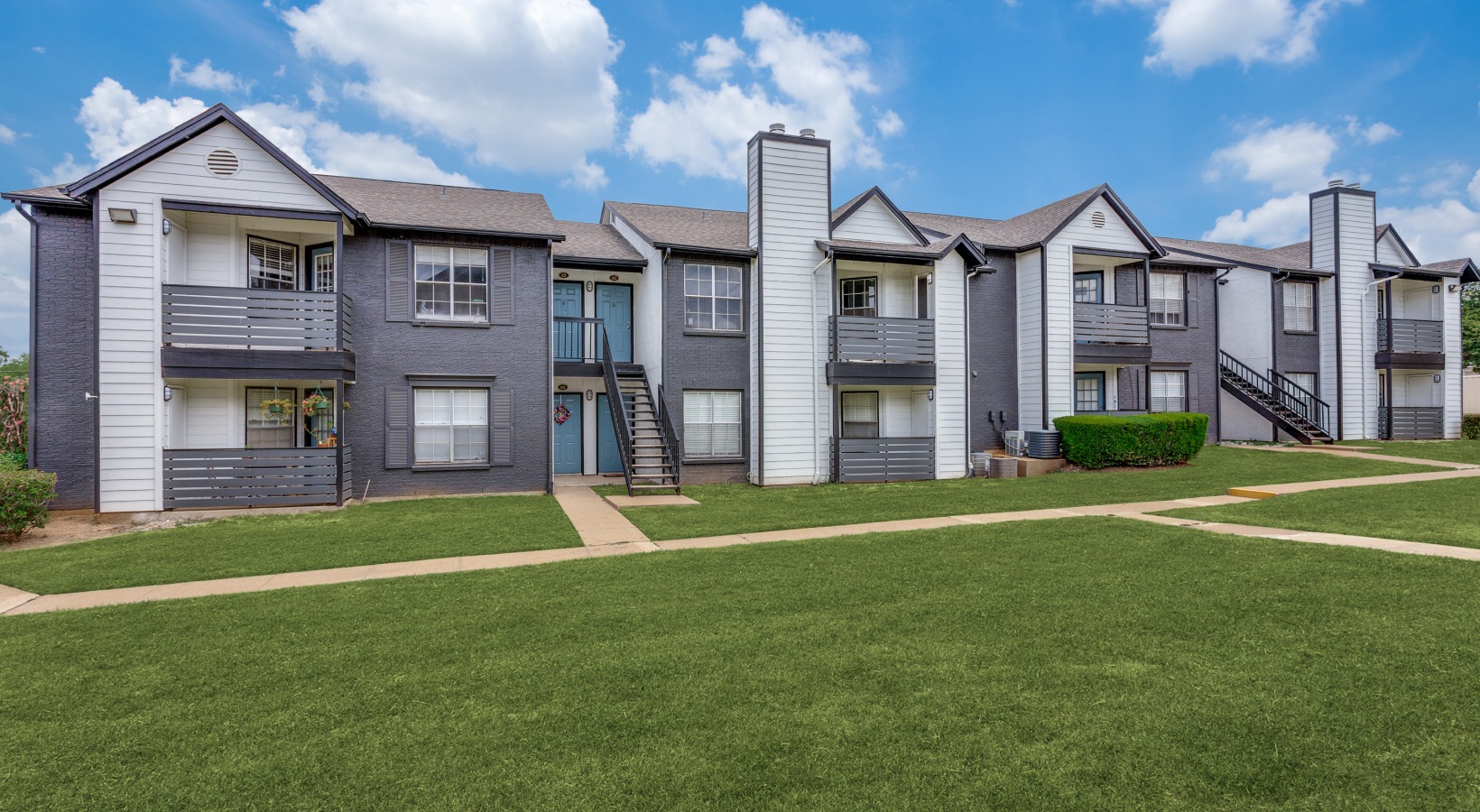 the exterior of an apartment complex with grass and trees at The Westley
