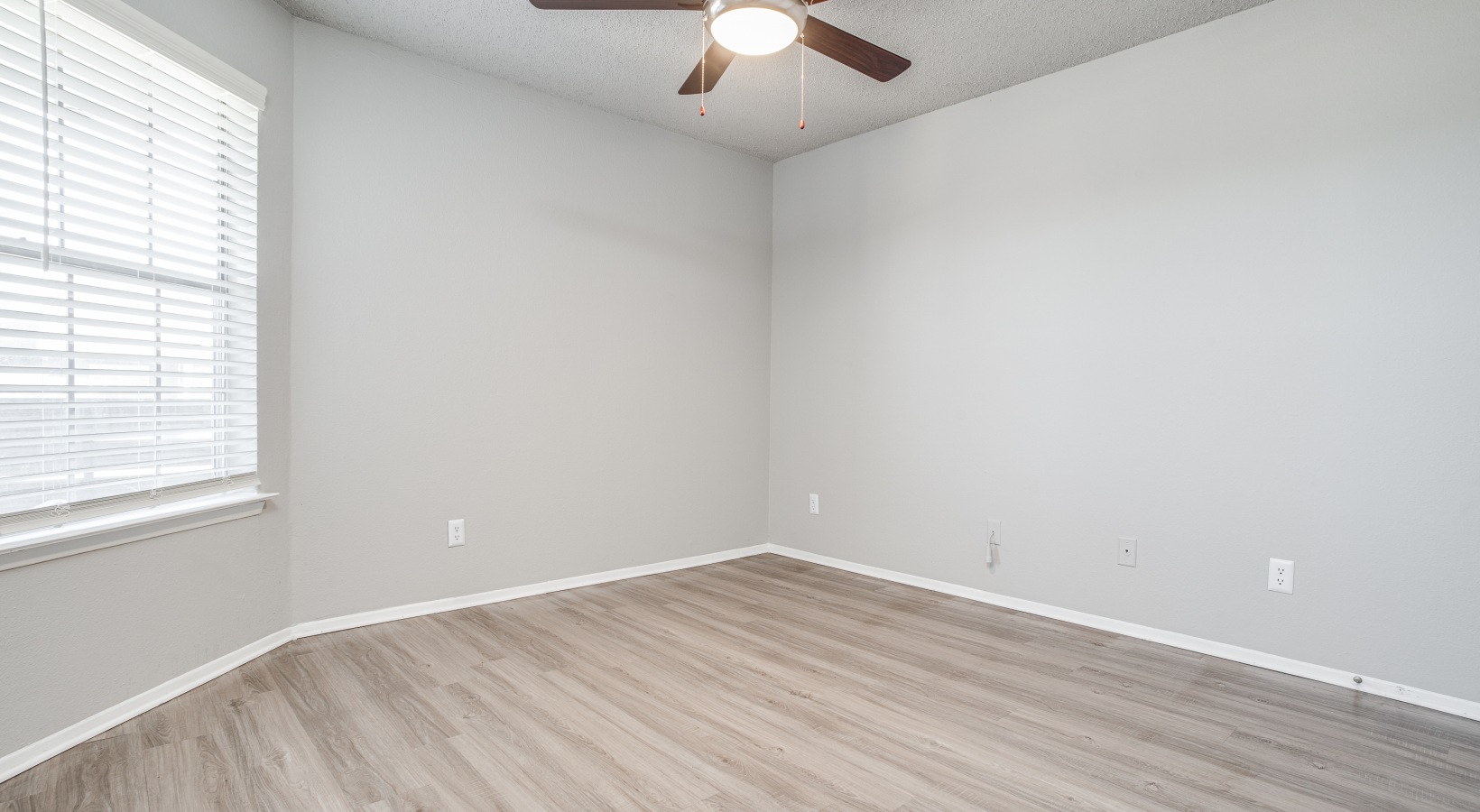 empty room with ceiling fan and hardwood floors at The Westley